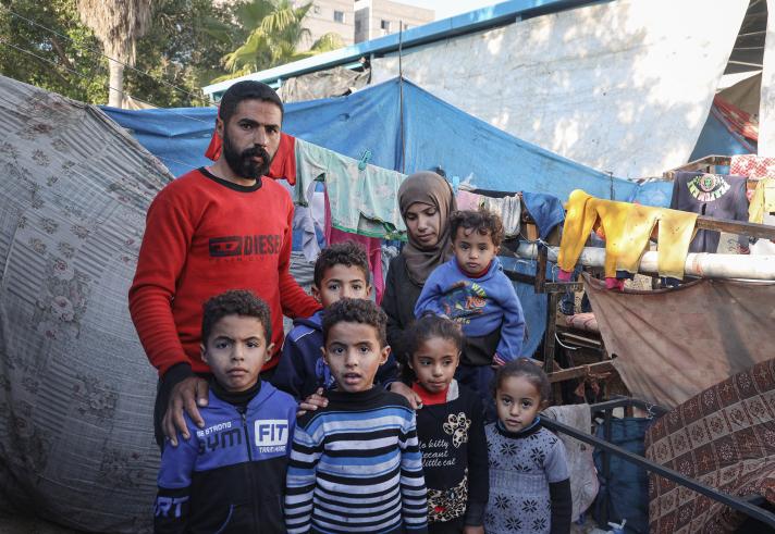A family with several young children outside a makeshift tent.