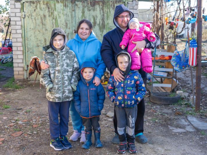 Olena, her husband and 4 children standing outside their house.
