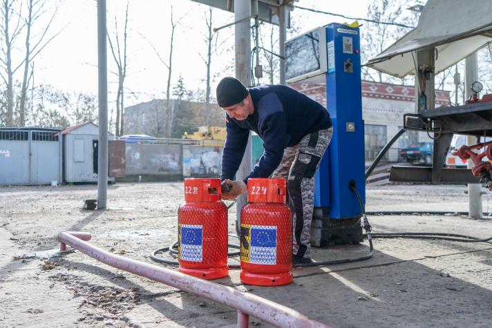 A man refilling 2 gas cylinders at a gas station.