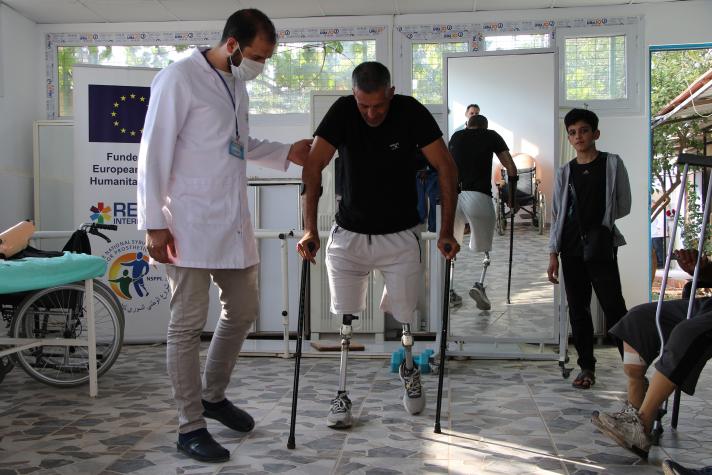 Mustafa helped by a doctor while learning to walk with protheses.