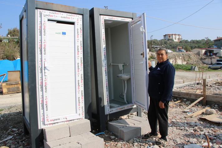 A man in front of 2 makeshift toilets.