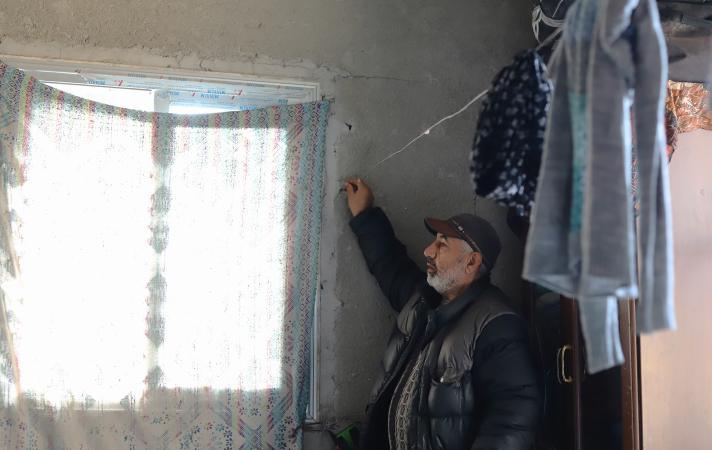 Rafiq is hanging clothes to dry in his family’s damaged flat.