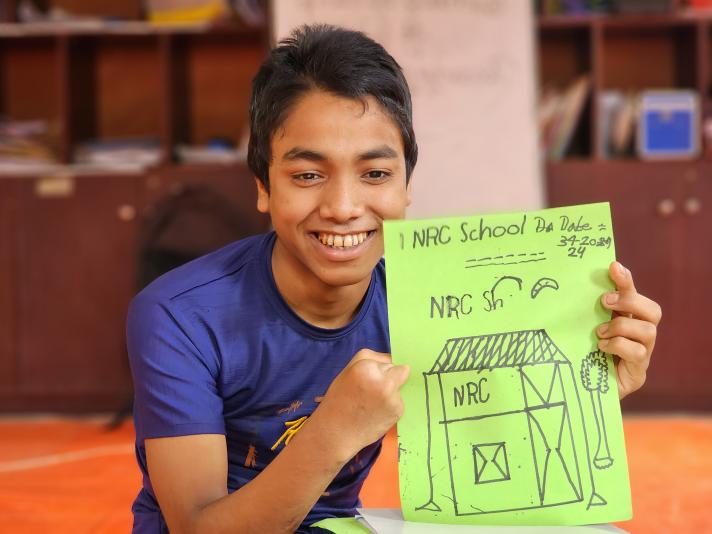 Robi holding up a pen drawing while smiling.