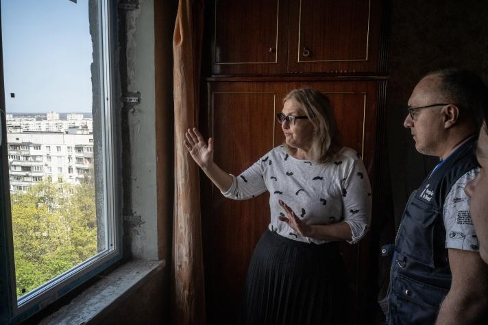 Larysa and her husband standing in front of a window looking outside.