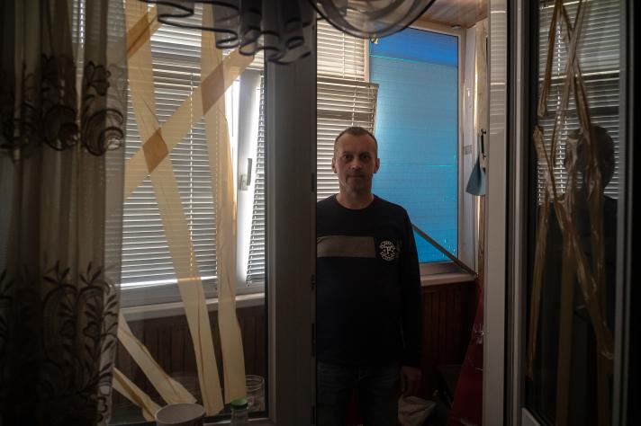Dmytro standing in front of a window. The glass is being held together with tape.