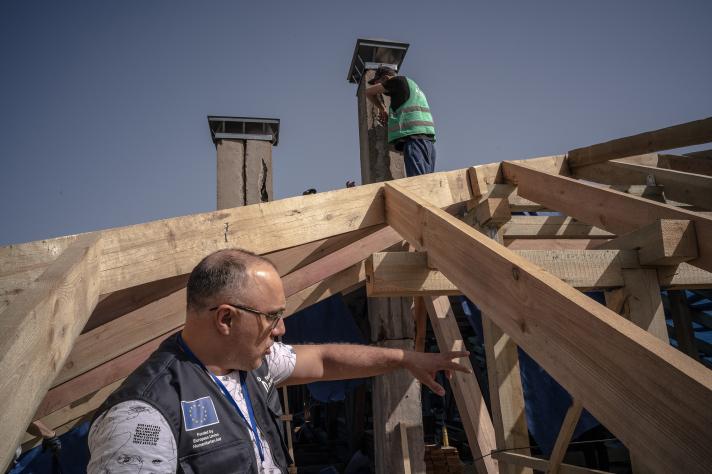 An aid worker standing inbetween rooftop beams.