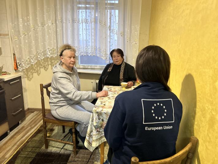 Elena and Svitlana sitting at a table speaking to an aid worker.