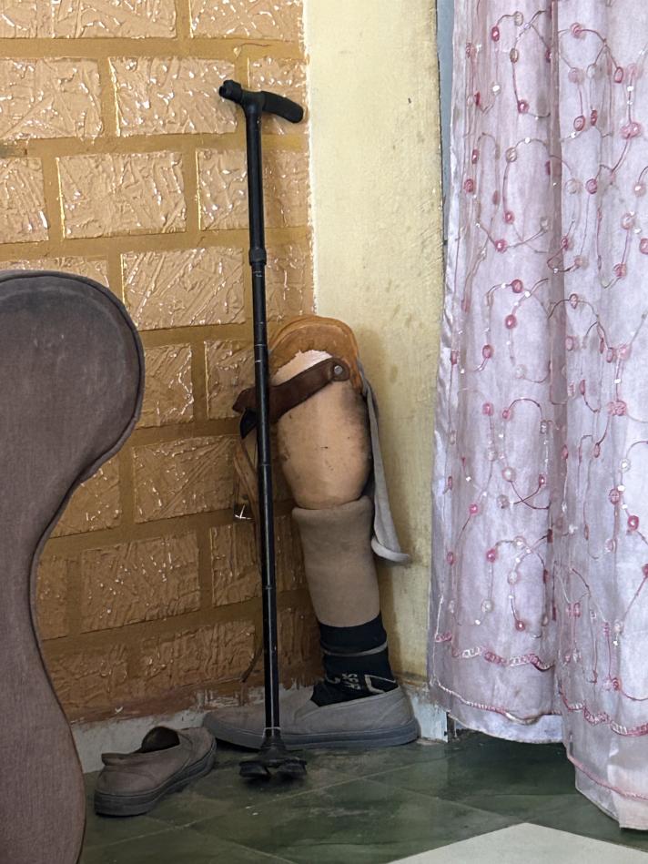A prosthetic leg standing in a corner with a walking stick.