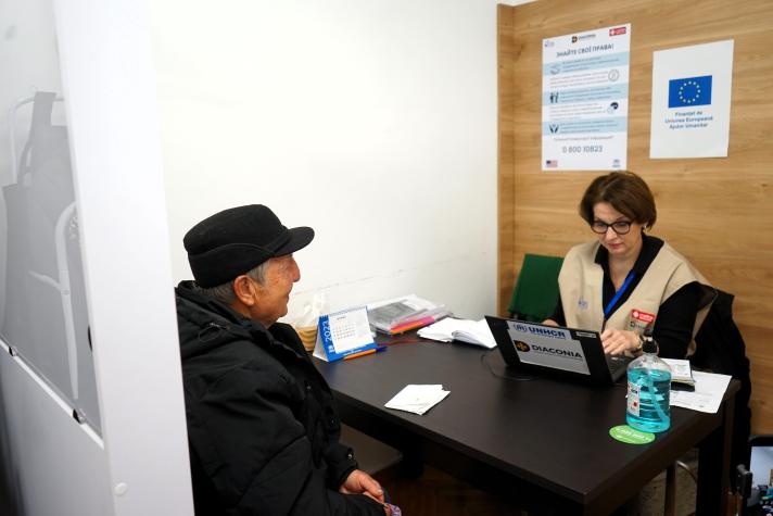 Anatolii sitting at a desk with an aid worker.