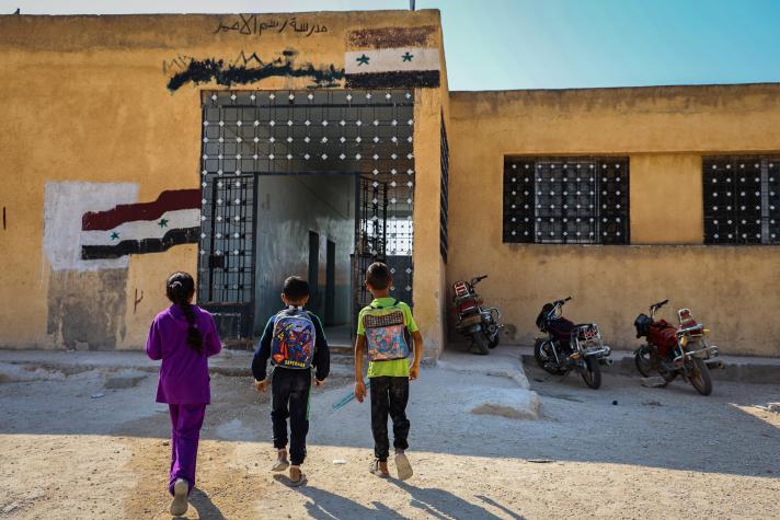 3 children walking towards the entrance of the school.