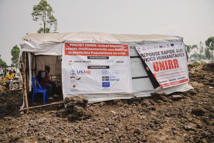 A tent used for counseling and education, 2 big posters on it with the names of the donor organisations.