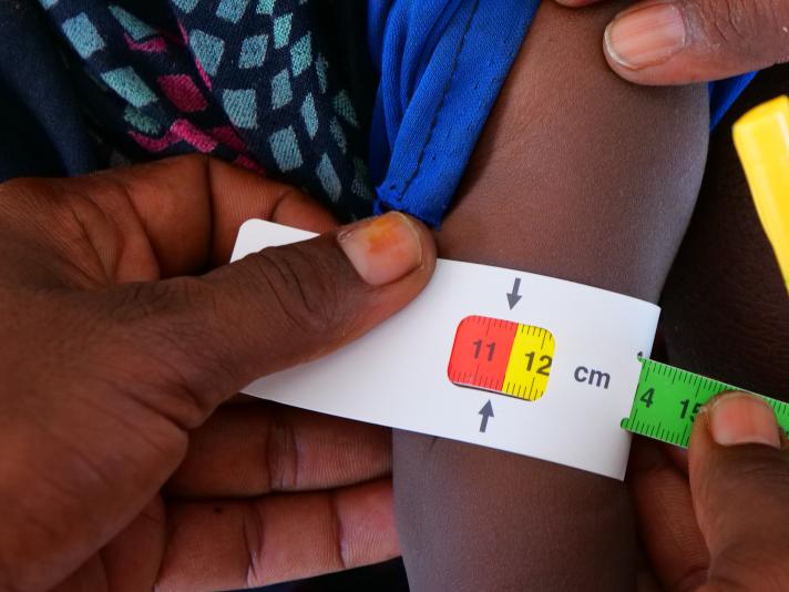 An example of a MUAC band being used. The band has stopped at red, indicating acute malnutrition. 