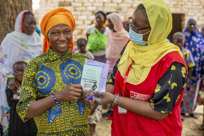 A pregnant woman receives her health record and a prescription following her prenatal consultation.