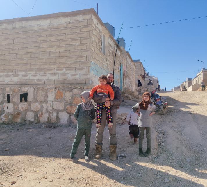 A family in a dusty street, standing in front of a building.