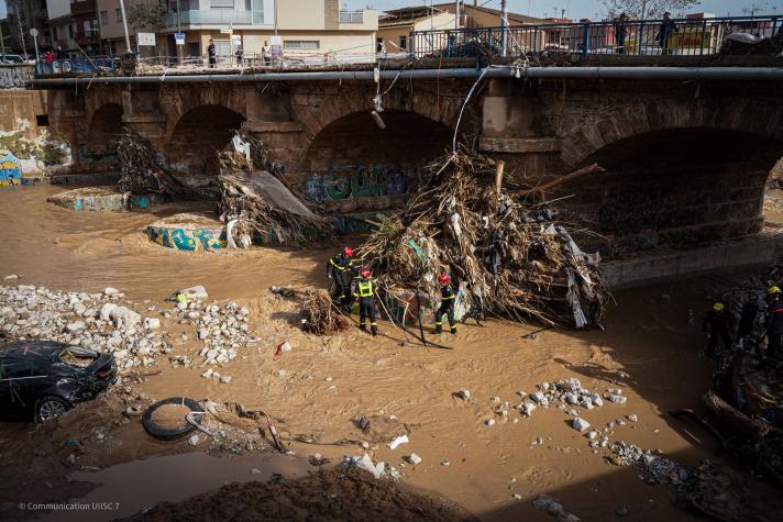 Debris in the mud in front of a bridge.