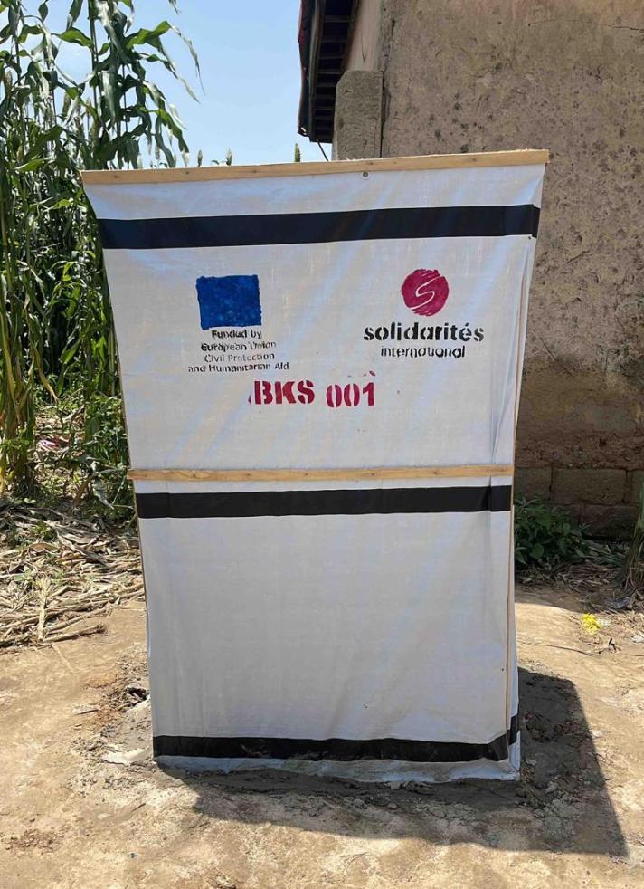 A latrine covered in a sheet with logos.