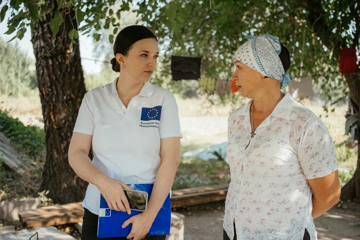 Svitlana and Ivanna talking while standing in the shadow under a tree.