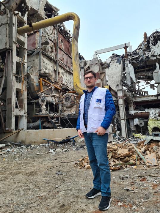 Volodymyr, EU humanitarian expert, in front of a destroyed building.