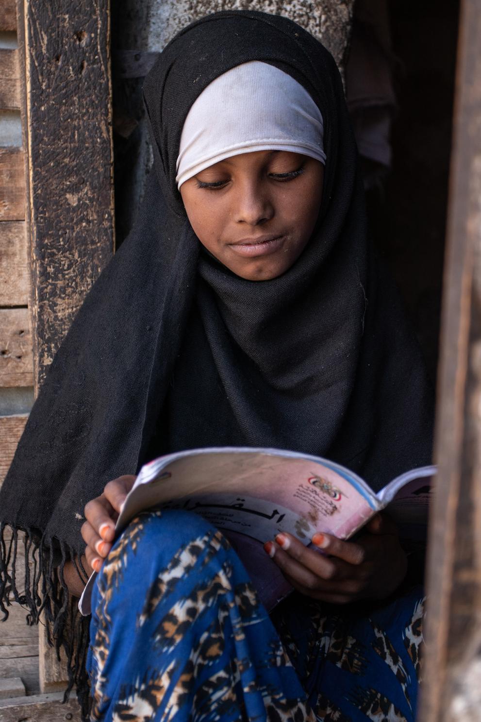 Na’aem reading in one of her schoolbooks