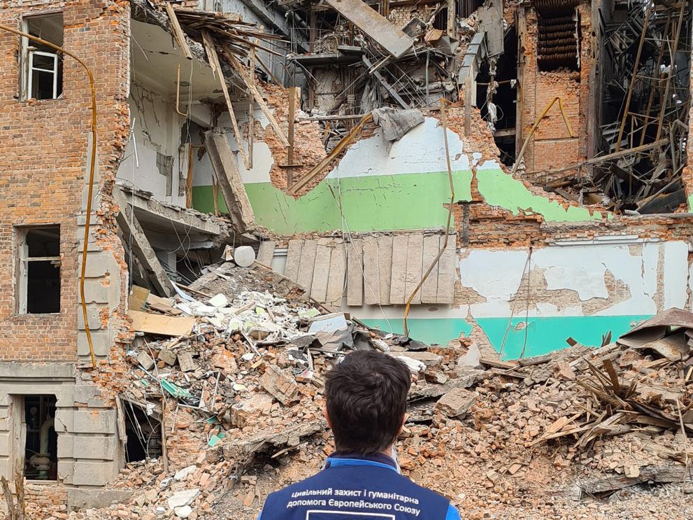 Aid worker looking at destroyed apparment building