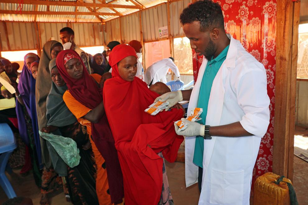 Woman standing in line while a doctor hands out ready-to-use therapeutic food