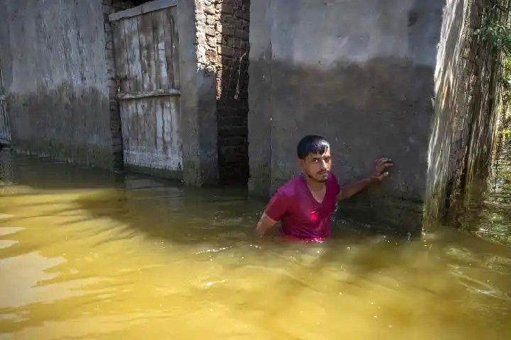 A man wades to his home in the inundated village of Sain Dad in Sindh’s Mirpur Khas district.