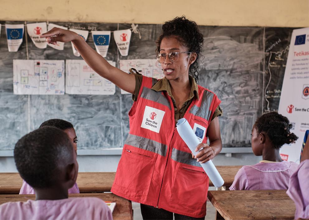Mirana R’Abel in a Save the Children vest with children in a school classroom