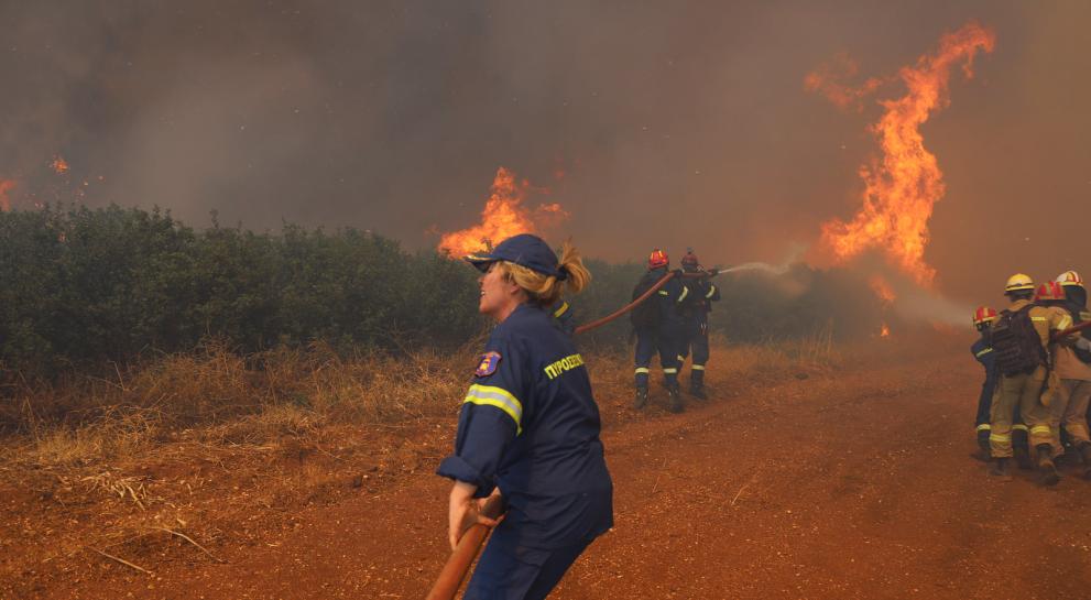 Woman firefighter, in the background a wildfire.