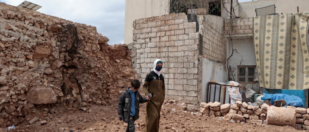 Wafaa and her son Abdullah walk among the remains of their home in the town of Sarmada.