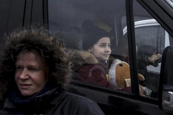 Woman in front of a bus with a child inside it