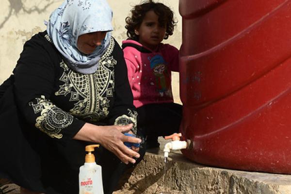 Woman and child tapping water from a tank
