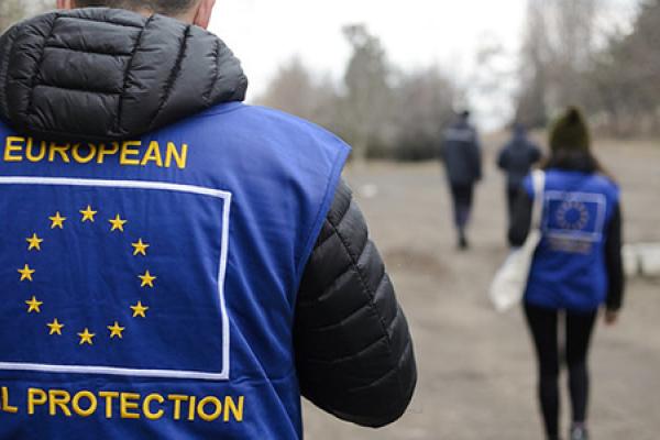 View off the back of a person wearing a vest with the EU Civil Protection logo