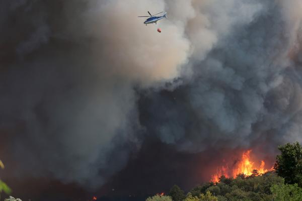 Helicopter dropping water on a fire on a hill