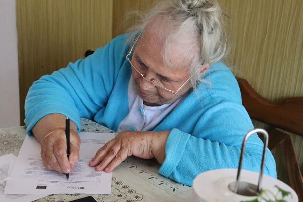 Ludmila sitting at a table while writing on a document