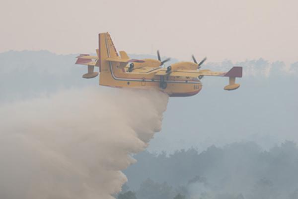 Plane dropping water on top of a wildfire