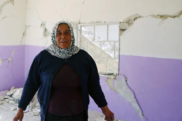 Photo of Alifa standing in her empty damaged house