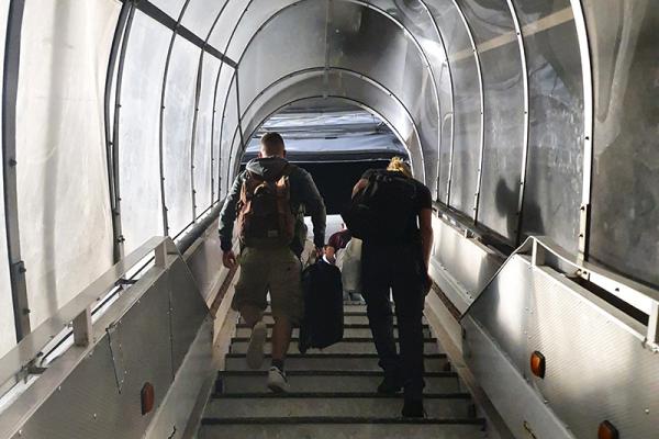 People walking up a stair to enter a plane