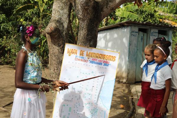 Irma Leina, a 6th grader, points to the multi-risk map her class drew.