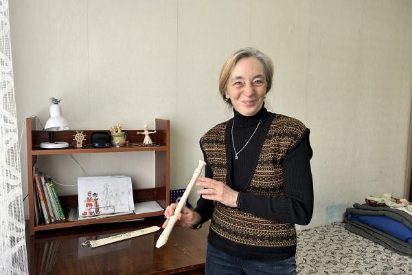 Yuliia, in her daughter´s room, holding a  blockflute. In the background a bed and a desk.