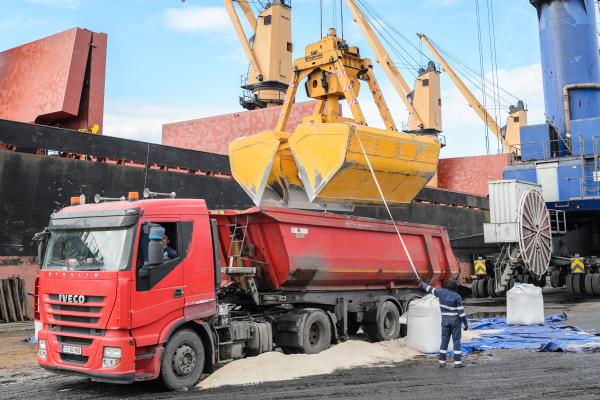 A crane unloading salt from a cargo ship (in the background) into a truck.