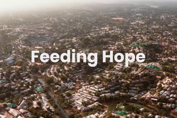 Feeding Hope text on an aerial view of a tropical village